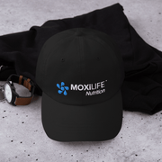 Moxilife Nutrition Black Podium Baseball Hat sitting on counter and black shirt